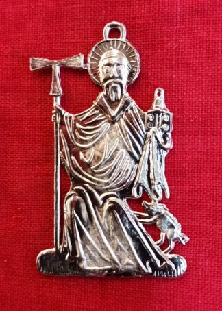 St. Anthony badge. The saint is seated. He holds a staff surmounted by a tau cross in his right hand. His left holds a book and a bell. A small pig jumps up towards him on his left side.